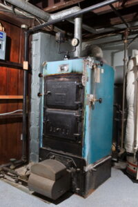 Old furnace unit installed in a basement utility area, representing a residential heater installation setup.