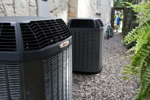 Two outdoor heat pump units installed alongside a house, representing the need for regular heat pump maintenance.