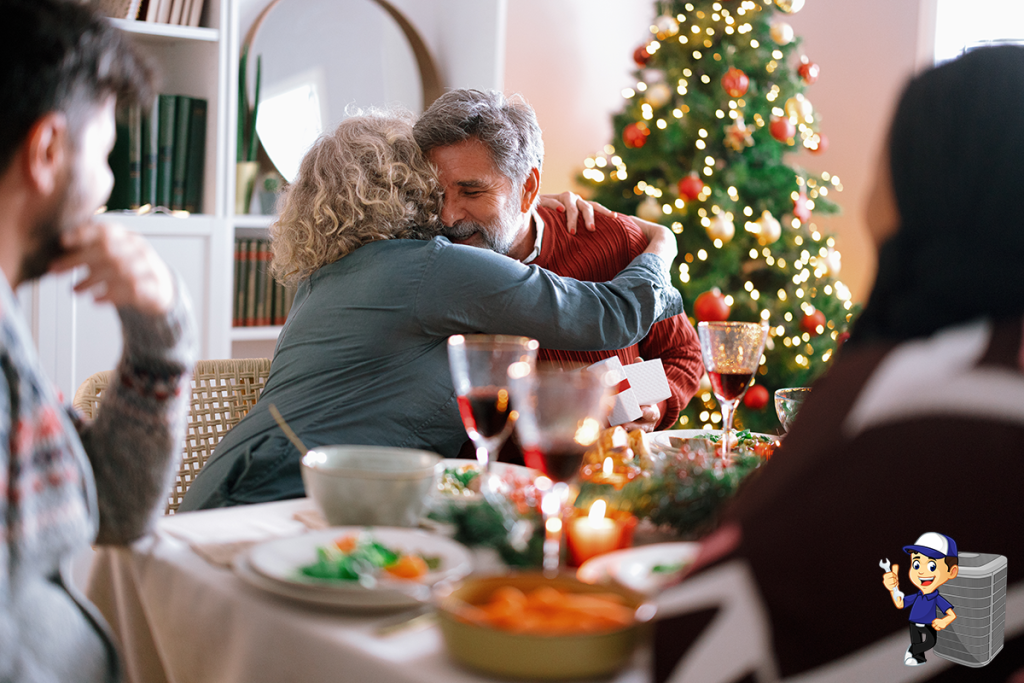 Smiling grandmother handing a wrapped Christmas present to her husband during a festive family dinner.